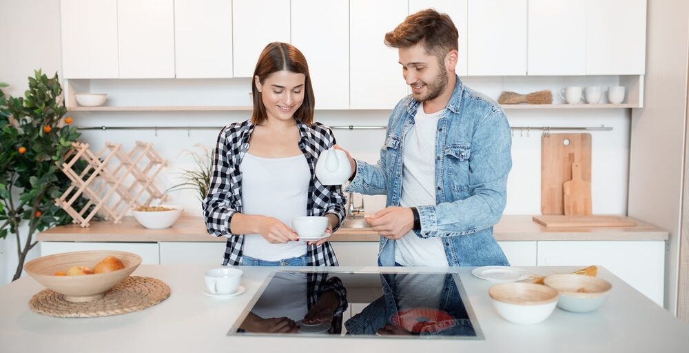 young happy man and woman in kitchen, breakfast, couple together in morning, smiling, having tea young happy man and woman in kitchen, breakfast, couple together in morning, smiling, having tea